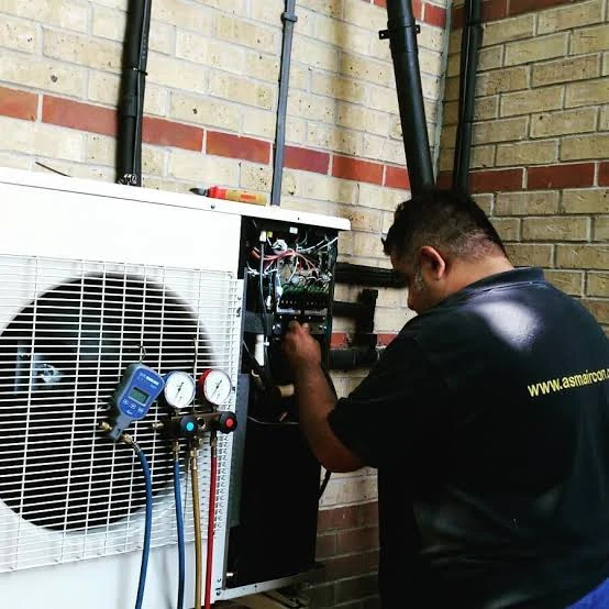 Technician using pressure gauges during air conditioner service